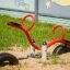 Équipement de jeu rouge SeeSaw sur sol sablonneux avec une fresque en arrière-plan.