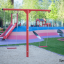 Youth Double Swing sur une aire de jeux avec des équipements colorés.