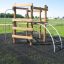 Sherwood wooden playhouse avec structure d'escalade et échelle sur une aire de jeux herbeuse.