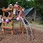 Enfants jouant sur Sherwood wooden playhouse dans un parc.