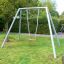 Silver Single Swing dans un jardin verdoyant avec un siège rouge.