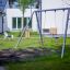 Silver Double Swing dans une aire de jeux entourée d’herbe verte et d’équipements de jeu.