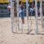 Un enfant jouant sur un Yellowstone wooden playhouse dans une aire de jeux sablonneuse.