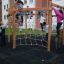 Des enfants jouent sur Yellowstone wooden playhouse dans une aire de jeux.