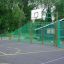 Terrain de basket extérieur avec des clôtures métalliques vertes, présentant l'installation de basket Shea.