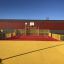 Aire de jeux Maracana avec surfaces rouges et jaunes, équipée d’un terrain de basket et de clôtures de sécurité i