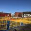 Une grande structure de terrain de jeux extérieur avec plusieurs clôtures métalliques jaunes et un revêtement en caoutchouc coloré.