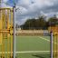 Aire de jeux Maracana avec clôture métallique jaune et terrain central ouvert.