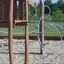 Une structure de jeu en bois avec des éléments d'escalade métalliques sur une surface sablonneuse de la série Alv.