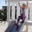 Fille glissant sur le toboggan Nature Ship Sandbox, wooden playhouse