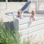 Deux filles jouant dans un Nature Ship Sandbox, wooden playhouse sur une aire de jeux sablonneuse.