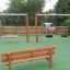 Larchwood Bench dans une aire de jeux avec des balançoires en arrière-plan.
