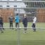 Enfants jouant au football sur le terrain de sport Goal entouré d’une clôture métallique.