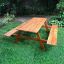Larchwood Table & Bench en extérieur sur l’herbe verte.