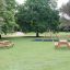 Larchwood Table & Bench dans un parc avec des arbres et une aire de jeux.
