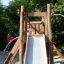 Enfant jouant sur un toboggan en bois Bergila dans un parc.