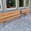 Banc, structure en acier, assise en bois à l'extérieur d'un bâtiment sur du gravier