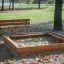 Banc, structure en acier à côté d'un bac à sable en bois dans un parc