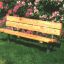 Banc en bois avec structure en acier dans un jardin avec des fleurs en fleurs.