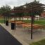 Espace de sièges extérieurs avec Table, Steel Construction et bancs sous une pergola en métal.