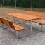 Ensemble d'extérieur Table & Bench avec sièges en bois et structure métallique sur une surface pavée.