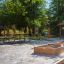 Ensemble de mobilier extérieur Table & Bench dans un parc avec un bac à sable à proximité.