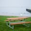Ensemble extérieur Table & Bench près d’un front de mer avec une zone herbeuse.