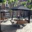 Ensemble Table & Bench Quadro dans une cour sous de grands parasols noirs.