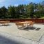 Disposition de tables et bancs de Table & Bench Quadro dans un environnement extérieur avec des arbres verts en arrière-plan