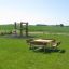 Table & Bench Quadro dans un parc verdoyant avec une aire de jeux en arrière-plan.