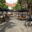 Sièges publics extérieurs avec ensembles Table & Bench Quadro sous des parasols.