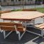Table hexagonale en bois avec six bancs fixés pour s'asseoir à l'extérieur.