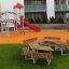 School Table & Bench dans un cadre de aire de jeux avec un toboggan et une structure d’escalade en arrière-plan
