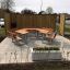 En extérieur, School Table & Bench installé dans une zone pavée avec des panneaux de séparation en bois.