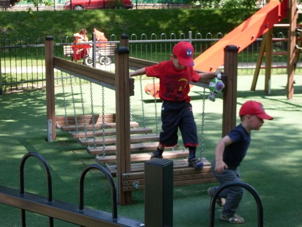 Enfants jouant sur un pont de terrain de jeu avec surface en gazon artificiel