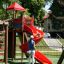 Enfants jouant sur un toboggan spiralé rouge dans une aire de jeux.
