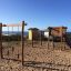 Maisonnette en bois Lianes sur une aire de jeux en bord de plage avec équipement d’escalade et de glisse.