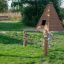 Fille grimpant sur l’équipement de jeu Diamond net dans un parc verdoyant.