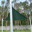 Sun Shade Triangle 3x3x3 Atlantis (Metal) installé dans une zone herbeuse avec de grands arbres en arrière-plan