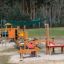 Aire de jeux extérieure avec auvent Sun Shade Square Atlantis (Metal) et structures de jeu en bois.
