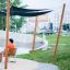 Sun Shades au-dessus des bancs du parc avec des personnes se détendant à proximité.