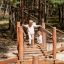 Équipement de terrain de jeu en bois avec pont suspendu Sahara et enfants jouant en extérieur dans une zone boisée