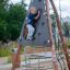 Un enfant grimpe sur le Tipi II climbing net dans une aire de jeux.