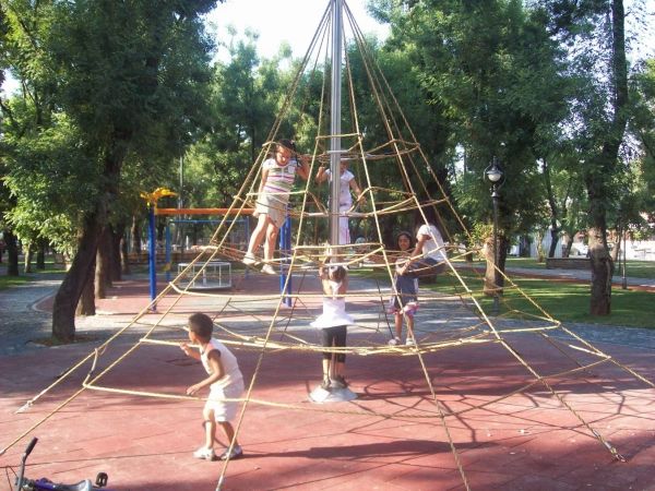 Des enfants jouent sur la surface de jeu Rubber Tiles 45 sous une grande structure d'escalade en corde.