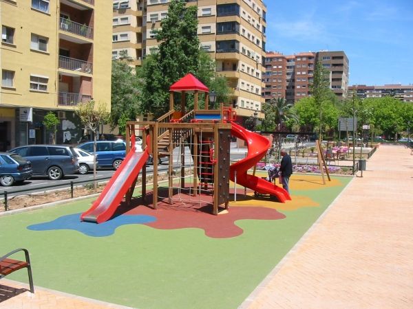 Aire de jeux avec toboggans rouges et revêtement coloré Wetpour 80 dans un cadre urbain.