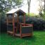 Maison de jeu extérieure en bois pour enfants 'Veranda House Nature' dans un cadre de jardin.