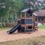 Knight's Castle Nature playhouse with slide dans une aire de jeux en forêt