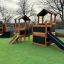 Knight's Castle Nature playhouse with slide dans une aire de jeux'