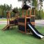 Maison de jeu en bois avec toboggan pour enfants dans une aire de jeux.