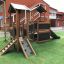Maison de jeu en bois avec toboggan dans une aire de jeux.